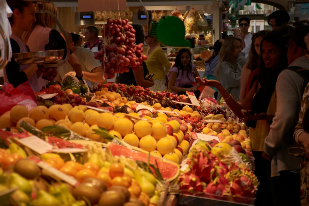 A group of people standing around a fruit stand