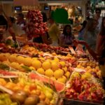 A group of people standing around a fruit stand