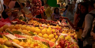 A group of people standing around a fruit stand