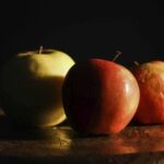 three apples sitting on top of a wooden table