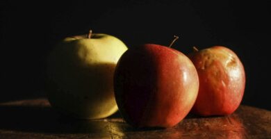 three apples sitting on top of a wooden table